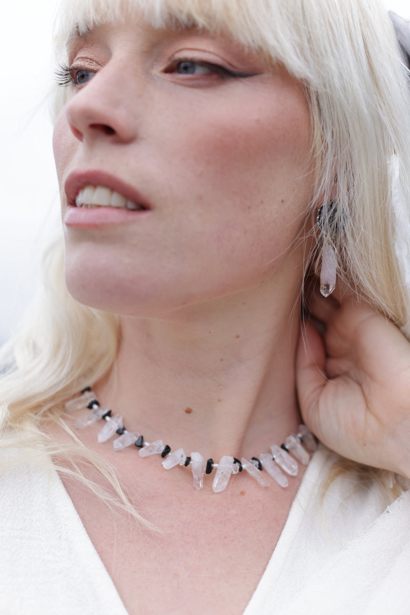 Close-up of a woman wearing a delicate necklace with small white stones.