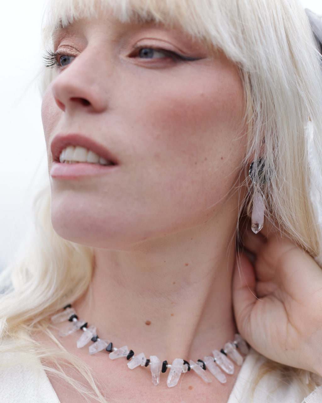 Close-up of a woman wearing a delicate necklace with small white stones.