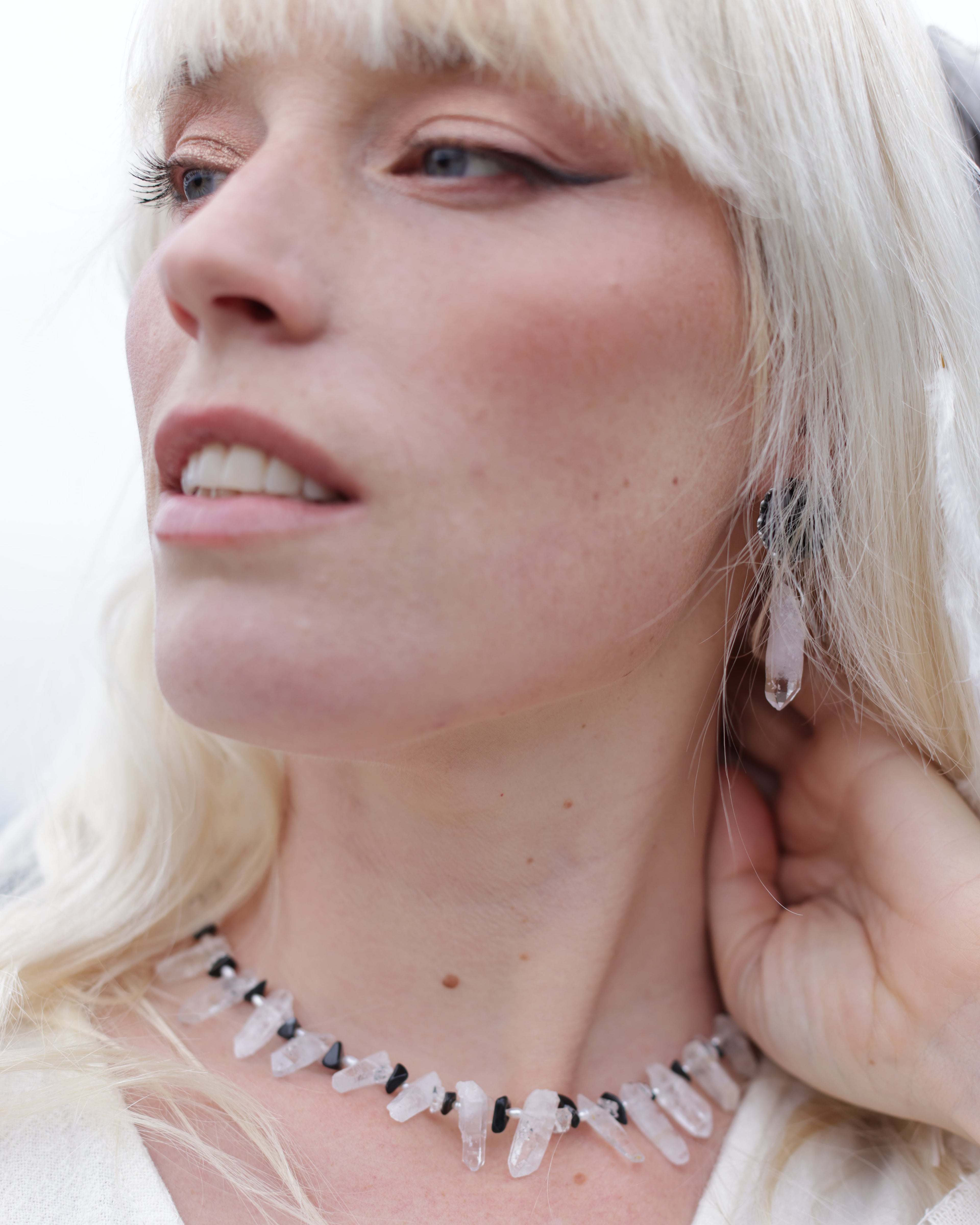 Close-up of a woman wearing a delicate necklace with small white stones.